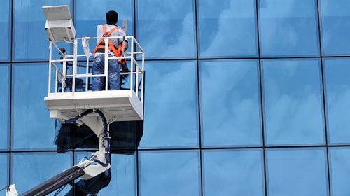Window cleaner working on a glass facade in a gondola building washing